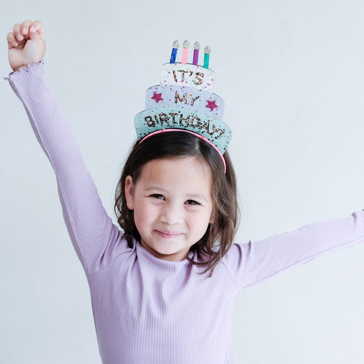 a kid wearing glittered design birthday cake headdress