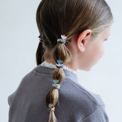 Child with braided hair using colorful tulip mini ponies ties on a light background