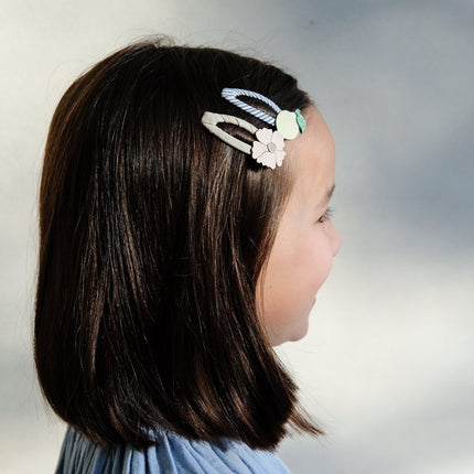 another lifestyle image of a Child with a decorative lemon blossom hair clip on a plain background