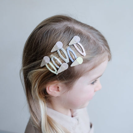 Child with decorative hair clips on a plain background