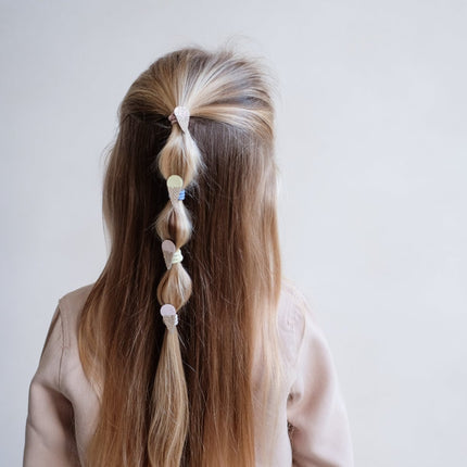 Person with long hair styled in a braid using ice cream mini ponies