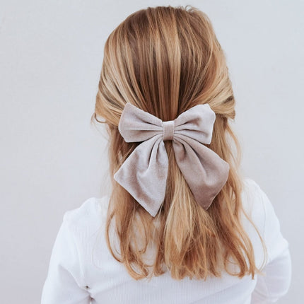 Blonde hair with a large beige bow on a plain background