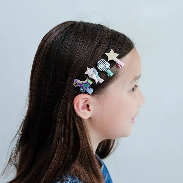 Girl with colorful hair clips in her hair against a light blue background