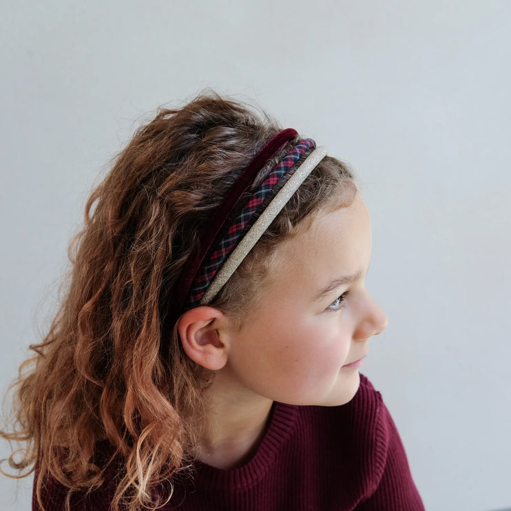 Child wearing a plaid headband with a plain background