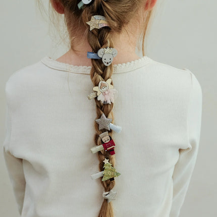 Person with braided hair adorned with various decorative hair clips on a plain background