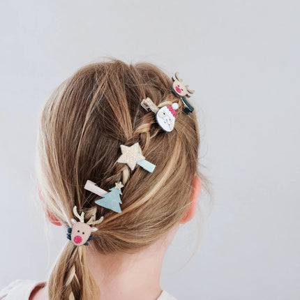 closer look of a kid wearing decorated hair clips in a braid against a plain background