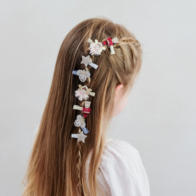 Person with decorative hair clips in a braid on a plain background
