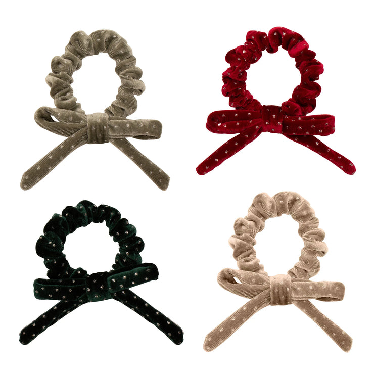 Four velvet hair scrunchies with bow designs in different colors on a white background.