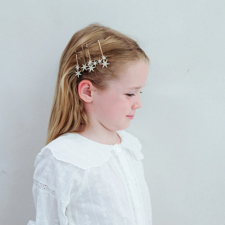 Young girl wearing star-shaped hair accessories against a plain background