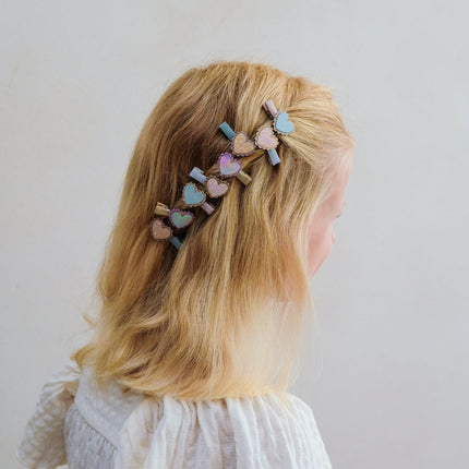 A child wearing a decorative hair clip with pastel heart charms 