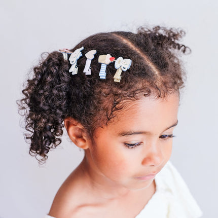 A girl wearing five small decorative hair clips in pastel colors