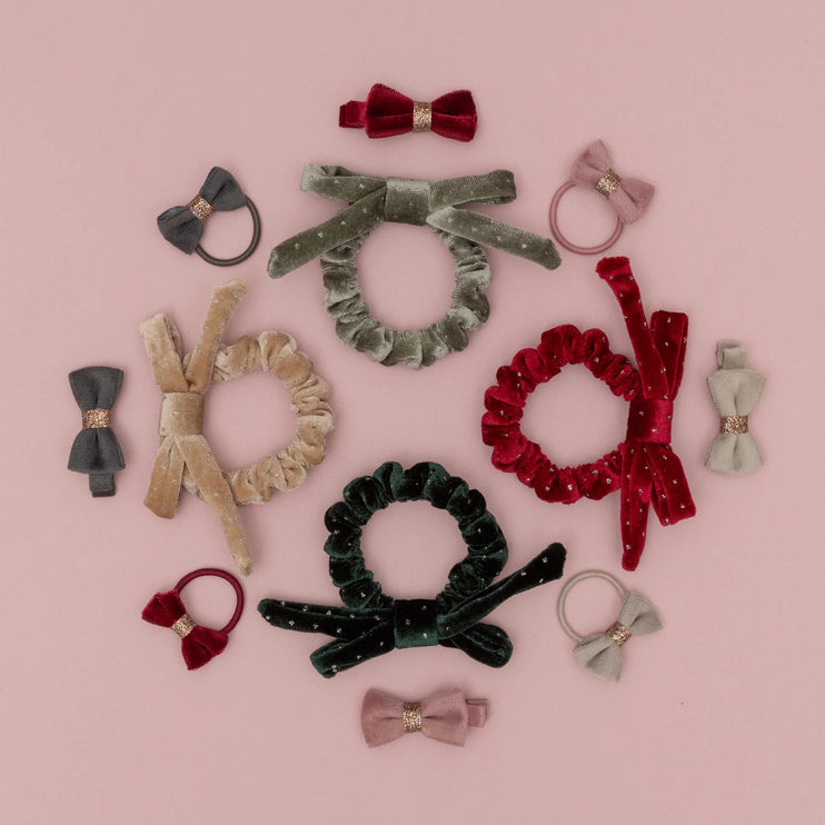 Collection of hair accessories including scrunchies and bows on a pink background