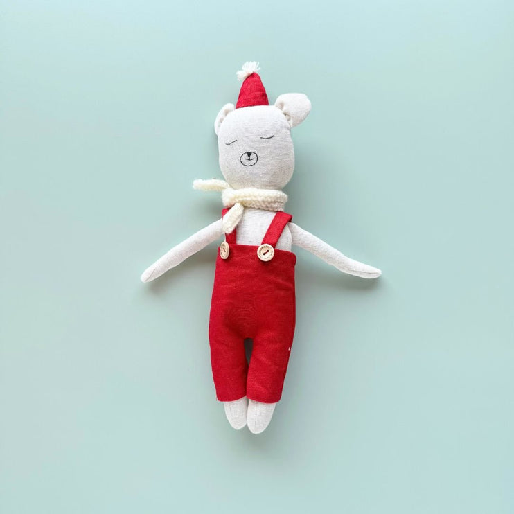 Snowy handmade bear doll wearing a red Santa hat and overalls and white scarf