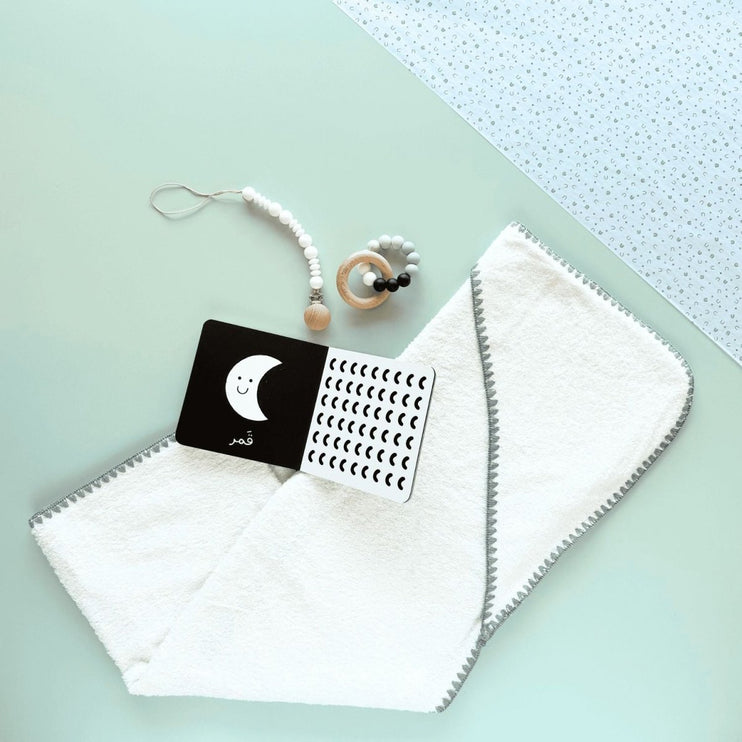 Baby items including a white blanket, with arabic book, and wooden silicon teether 