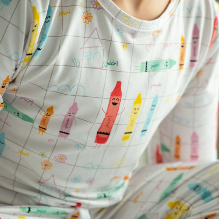 A child wearing a Alwan pajam with colorful crayon illustrations and text.