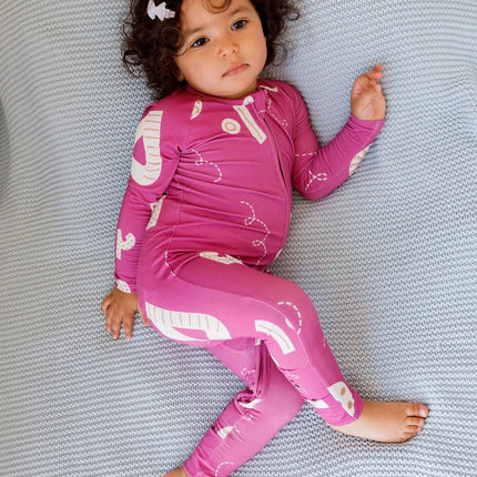 Child wearng Arqam romper laying on a grey blanket.