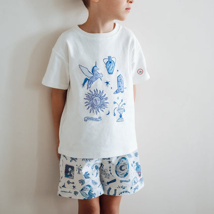 Child wearing a white t-shirt and shorts with blue graphics 