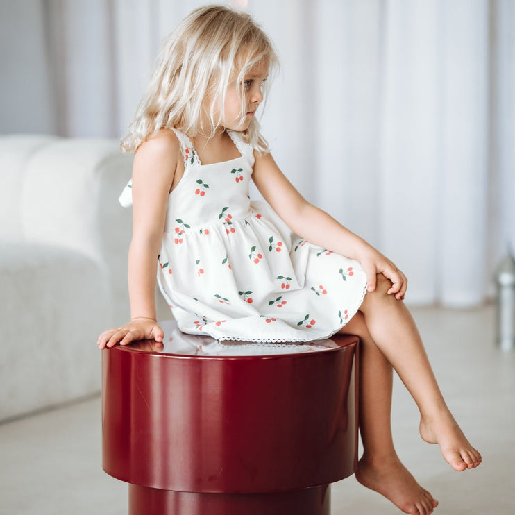 Young girl in a white dress with cherry print 