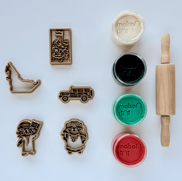 Set of cookie cutters and colored dough on a white surface