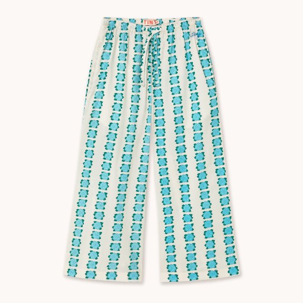 Off white pants with blue flowers striped down the legs