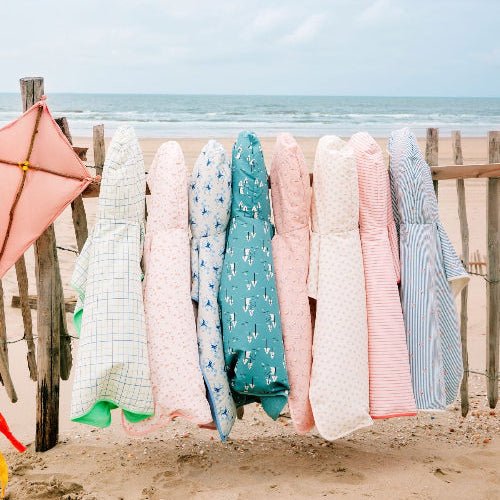 Colorful Swim Ponchos hanging on a wooden fence featuring various pattern prints 