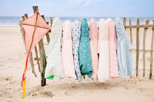 Colorful Swim Ponchos hanging on a wooden fence featuring various pattern prints 