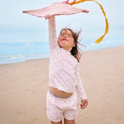 Playful baby girl wearing Cream with butterflies print longsleeves top and matching swim short