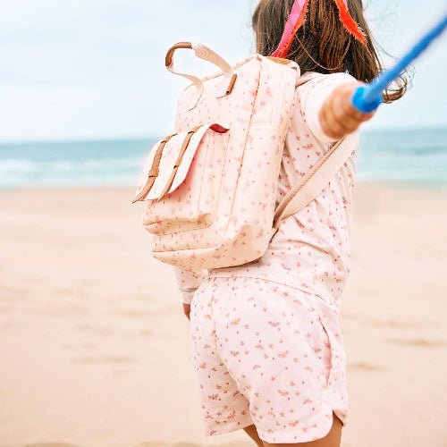 Girl wearing matching cream with butterfly print long-sleeve top and shorts with matching backpack.