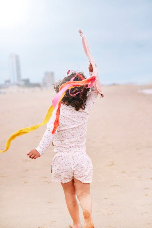 Playful baby girl wearing Cream with butterflies print longsleeves top and matching swim short