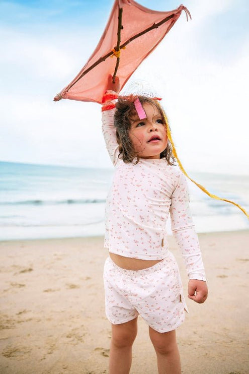 Playful baby girl wearing Cream with butterflies print longsleeves top and matching swim short