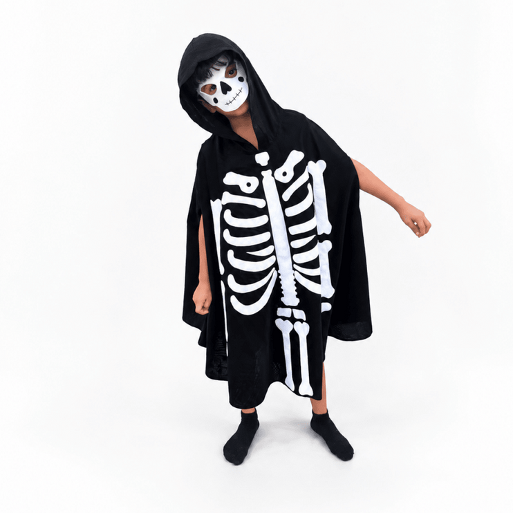 A child wearing a black hooded skeleton costume with a white printed rib cage and spine design, a white skull mask, black socks, and black shoes, standing against a plain white studio background.