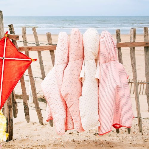 Colorful Girls Swim Ponchos hanging on a wooden fence featuring various pattern prints 