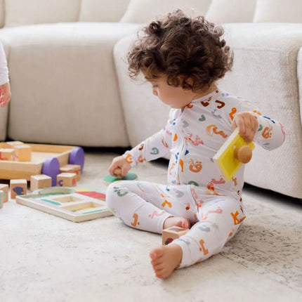 Child wearing Huroof onesie playing with toys on a carpeted floor