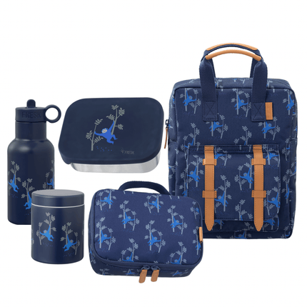 A coordinated nursery set in navy blue fabric with a repeating light blue monkey pattern, including a small backpack, lunch bag, water bottle, and food jar.