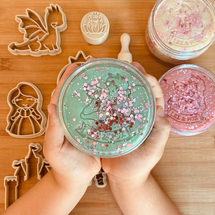 round glass jar filled with mint green playdough topped with pink and red glitter