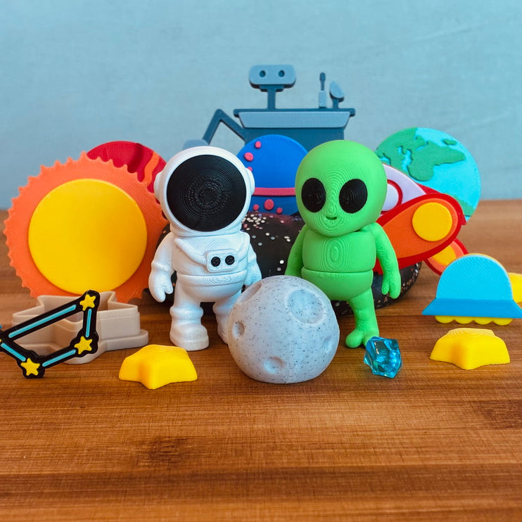 Colorful space-themed toys including an astronaut, alien, and solar system models on a wooden surface.