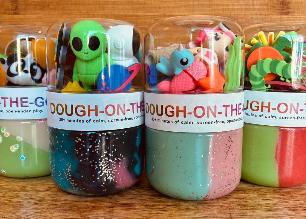 plastic jars filled with colorful dough-like play products and topped with cartoon figures