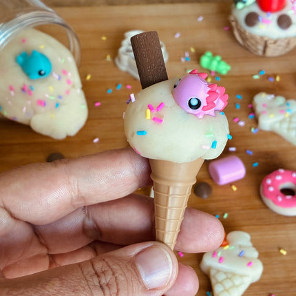 Hand holding a small ice cream cone toy with a character on top