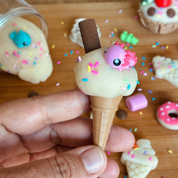 Hand holding a small ice cream cone toy with a character on top