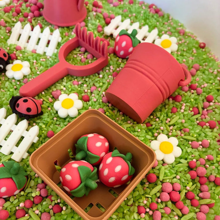Playful garden scene with red tools, strawberry-shaped candies, and green sprinkles 