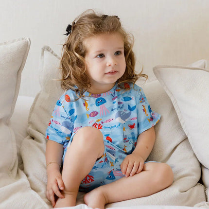 Child wearing a Kebr l Baher pajama sitting on a couch