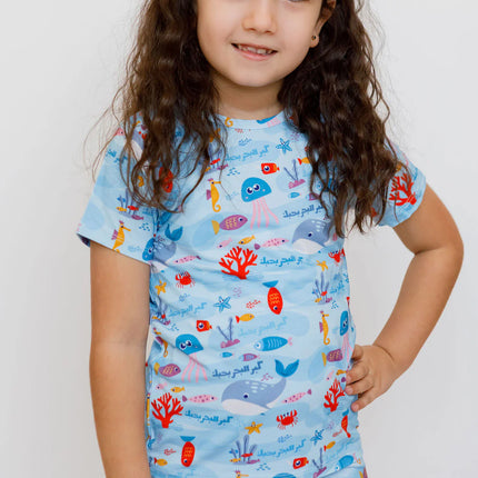 Child wearing a Kebr l Baher pajama set with ocean-themed design 