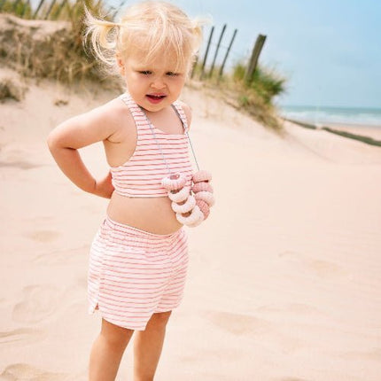 Cheerful Baby Girl wearing matching striped cream and peach bikini top and swim shorts