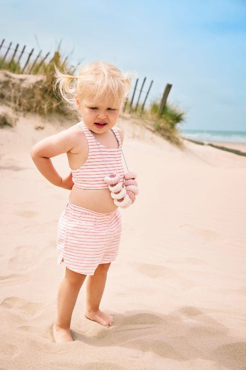 Cheerful Baby Girl wearing matching striped cream and peach bikini top and swim shorts