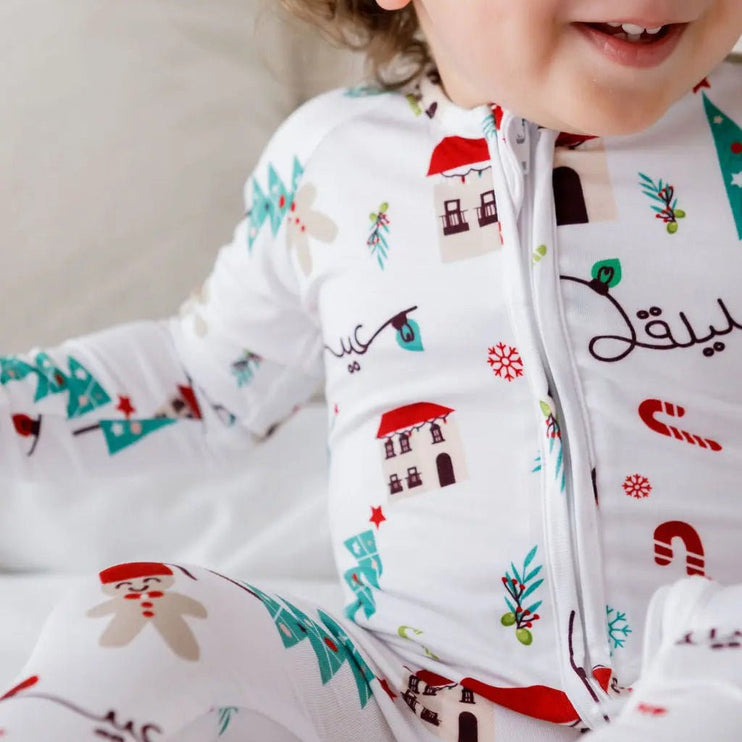 Child wearing a festive onesie with Christmas-themed designs on a neutral background