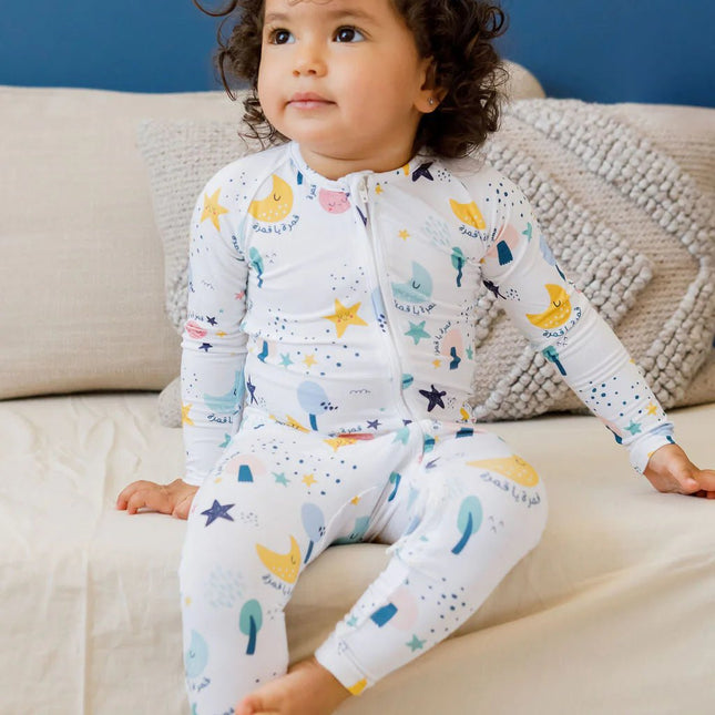 Child wearing a colorful Amara romper moon and stars-themed design.