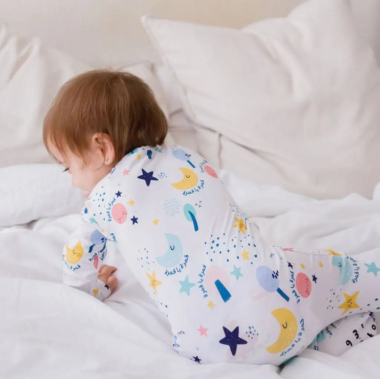Baby in a Amara onesie lying on a bed