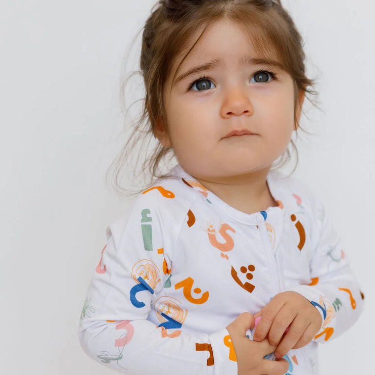 Child wearing a Huroof onesie with colorful patterns.