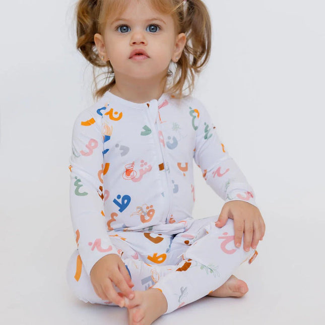 Child wearing a Huroof onesie with  prints.