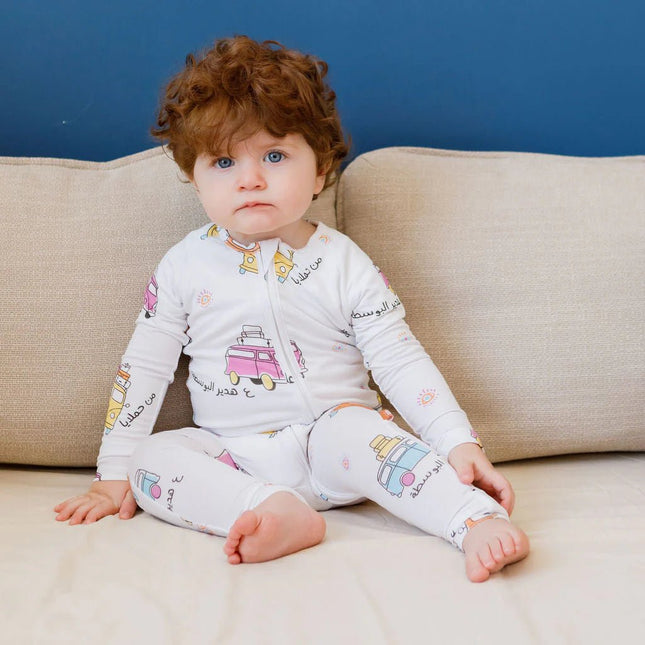 Child wearing a Bosta onesie with colorful graphics sitting on a beige couch.